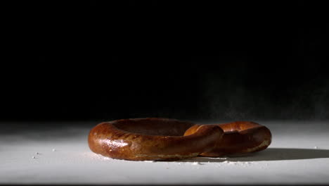 Pretzel-falling-onto-flour-on-black-background