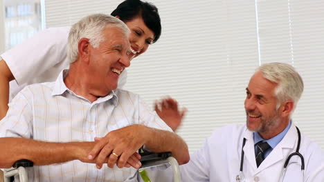 Doctor-talking-with-elderly-patient-in-a-wheelchair-being-pushed-by-nurse