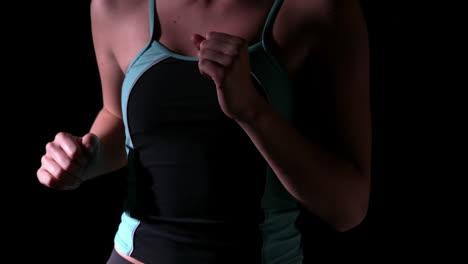 Woman-jogging-and-listening-to-music-against-black-background