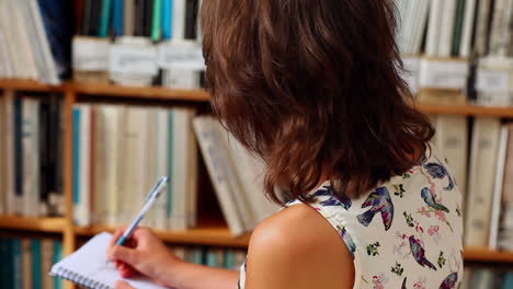 Young-female-student-writing-in-library-