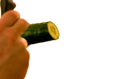 Hand-slicing-a-cucumber-on-white-background