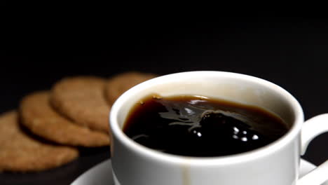 Café-Arremolinándose-En-Una-Taza-Al-Lado-De-Galletas