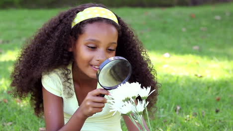 Little-girl-sitting-on-grass-inspecting-a-flower