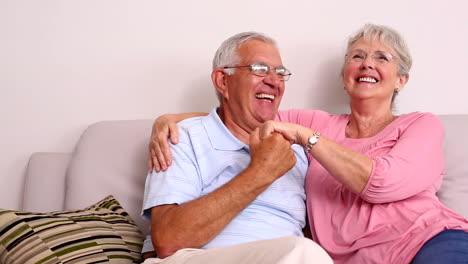 Senior-couple-sitting-on-sofa-hugging