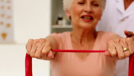 Nurse-showing-elderly-patient-how-to-use-resistance-band