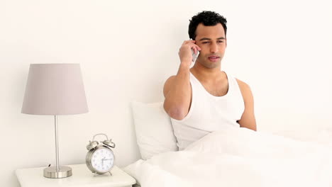 Happy-handsome-man-sitting-on-bed-phoning