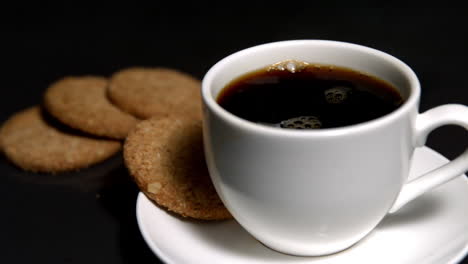 Café-Arremolinándose-En-Una-Taza-Al-Lado-De-Galletas