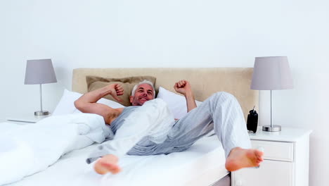 Refreshed-man-waking-up-and-looking-at-his-alarm-clock