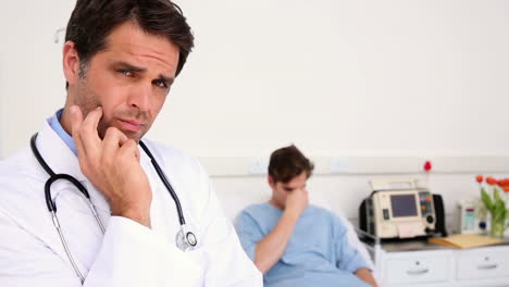 Sick-man-lying-on-hospital-bed-with-doctor-frowning-at-camera