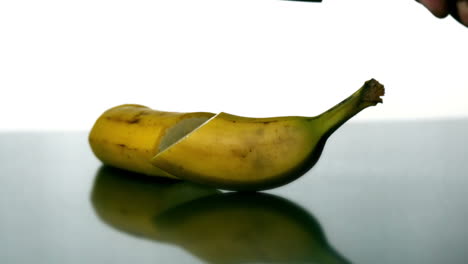 Man-slicing-banana-with-large-knife