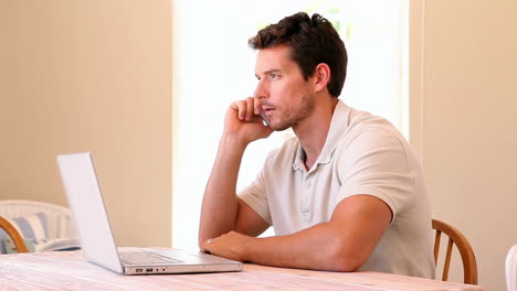Man-using-laptop-while-speaking-on-phone