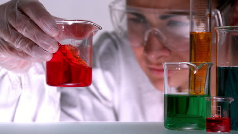 Scientist-swirling-red-liquid-in-beaker