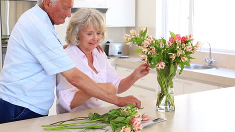 Ältere-Frau-Arrangiert-Mit-Ihrem-Partner-Blumen-In-Einer-Vase-