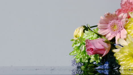 Bouquet-of-colourful-flowers-falling-onto-wet-surface