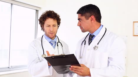 Doctors-discussing-something-on-clipboard