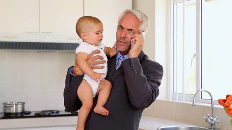 Businessman-holding-his-baby-and-talking-on-the-phone