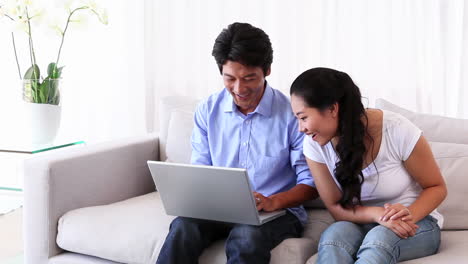 Asian-man-showing-his-girlfriend-something-on-laptop