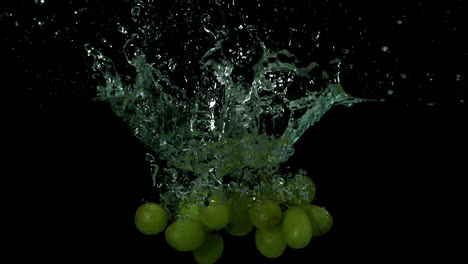 Uvas-Cayendo-En-Agua-Sobre-Fondo-Negro