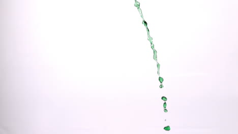 Green-water-pouring-across-white-background