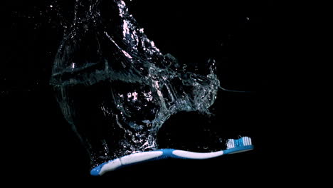 Blaue-Zahnbürste-Fällt-Ins-Wasser-Auf-Schwarzem-Hintergrund