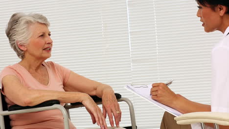 Nurse-talking-with-elderly-patient-in-a-wheelchair