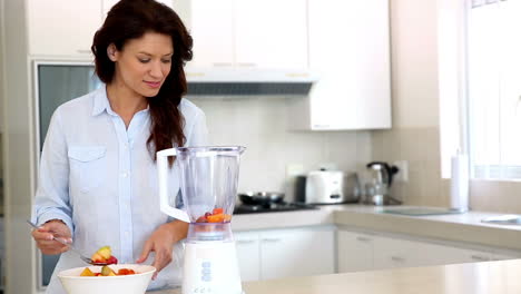 Pretty-brunette-making-a-smoothie-at-the-counter