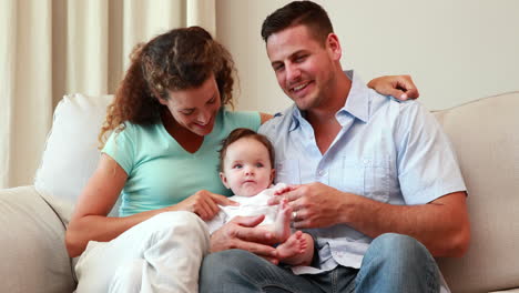 Young-parents-sitting-on-the-couch-with-their-baby-son