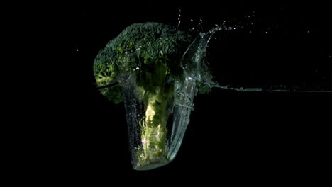 Broccoli-falling-in-water-on-black-background