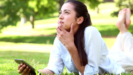 Pretty-girl-lying-on-the-grass-using-her-tablet