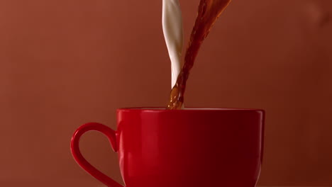 Té-Caliente-Y-Leche-Vertiendo-En-Una-Taza-Roja