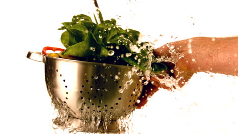 Water-pouring-over-salad-in-colander-held-by-hand
