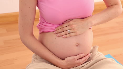 Mujer-Embarazada-Rubia-Sentada-Sobre-Una-Alfombra-Azul-