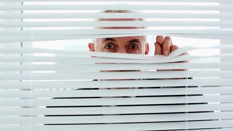 Businessman-spying-through-blinds-and-getting-caught-by-camera