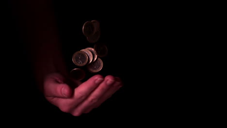 Hand-throwing-coins-and-catching-them-on-black-background
