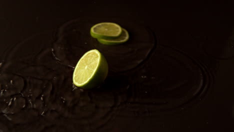 Lime-pieces-dropping-on-wet-black-surface