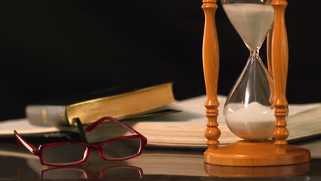 Reading-glasses-falling-beside-hourglass-and-bible