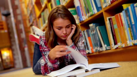 Estudiante-Tirado-En-El-Suelo-Leyendo-Un-Libro-En-La-Biblioteca