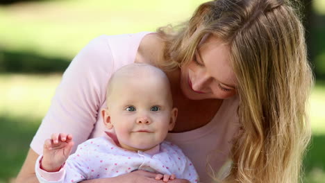 Happy-mother-holding-her-baby-girl-in-the-park