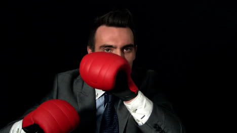 Businessman-punching-with-red-gloves-on-black-background