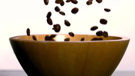 Coffee-beans-falling-into-wooden-bowl