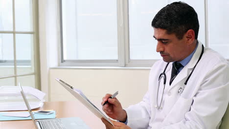 Doctor-sitting-at-desk-looking-at-file