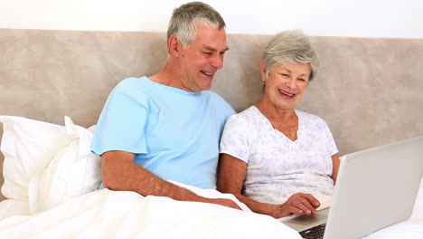 Glückliches-älteres-Paar-Sitzt-Im-Bett-Mit-Laptop