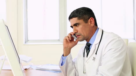 Doctor-working-at-his-desk-talking-on-the-phone