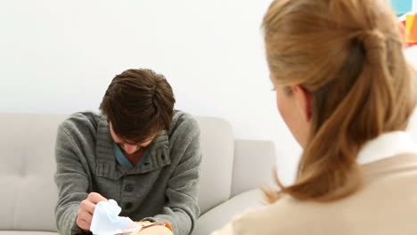 Young-man-sitting-on-sofa-talking-to-his-therapist