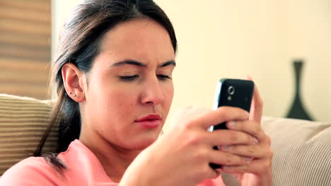 Pretty-brunette-relaxing-on-sofa-using-her-smartphone