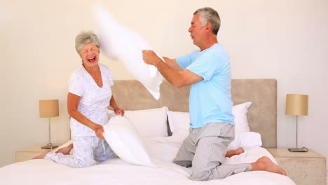 Happy-senior-couple-having-a-pillow-fight