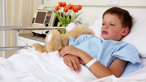 Little-sick-boy-lying-in-bed-with-teddy-bear