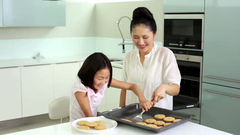 Mother-and-daughter-taking-cookies-from-baking-tray