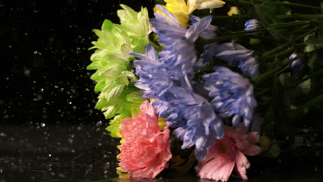 Bouquet-of-flowers-falling-onto-wet-black-surface