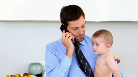 Geschäftsmann-Hält-Sein-Baby-Und-Telefoniert